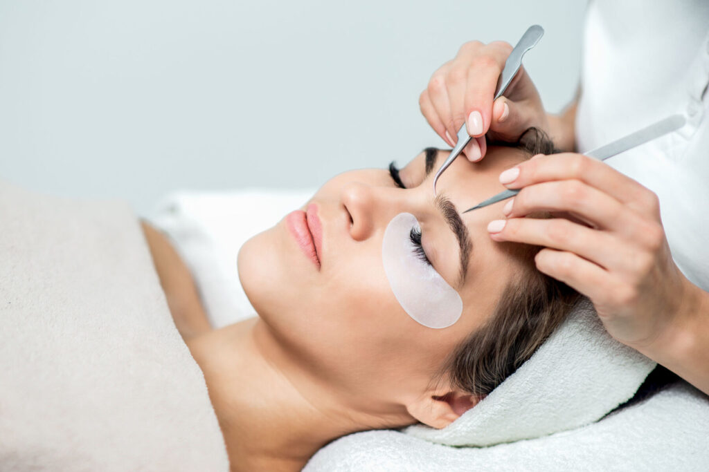 Hands holds tweezers for eyelash extensions.